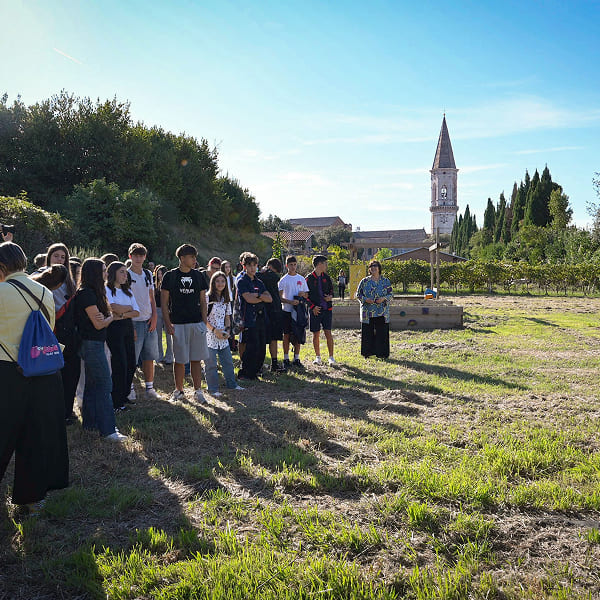 Group in a field listening to a man, church in background