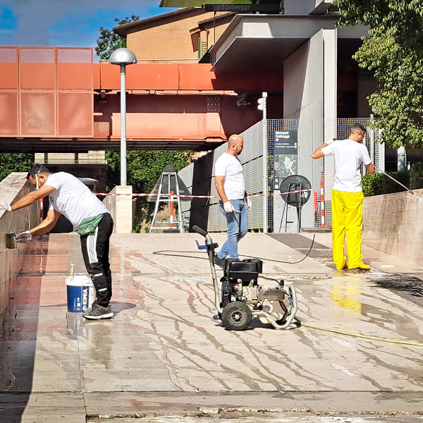 Three men cleaning a ramp with a pressure washer and sponges