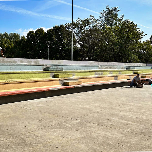 Two men repainting the stands of an arena