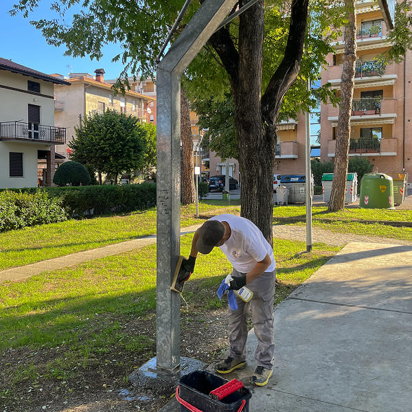 Man cleaning a basketball hoop in a residential green area