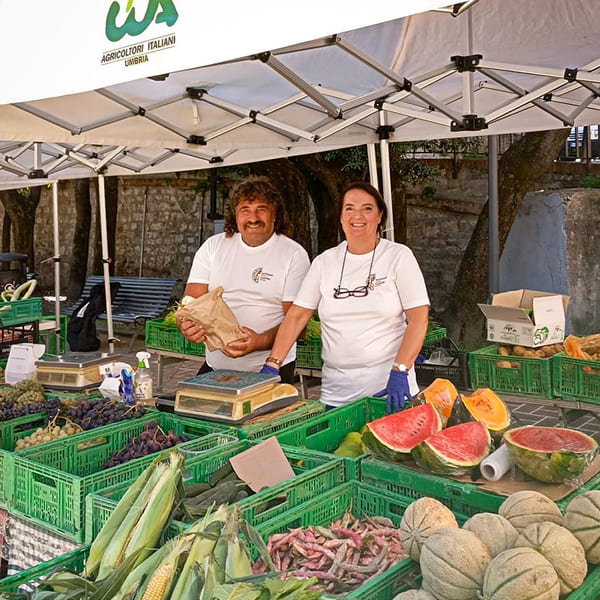 Two farmers behind a fruit and vegetable stand