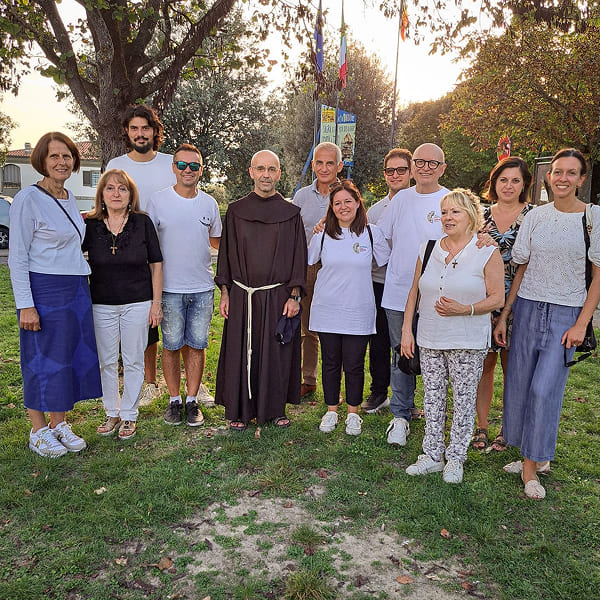 Group of volunteers, including a friar, in a park