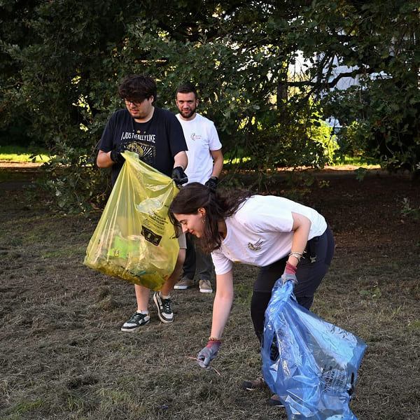 Three volunteers collecting trash in a field