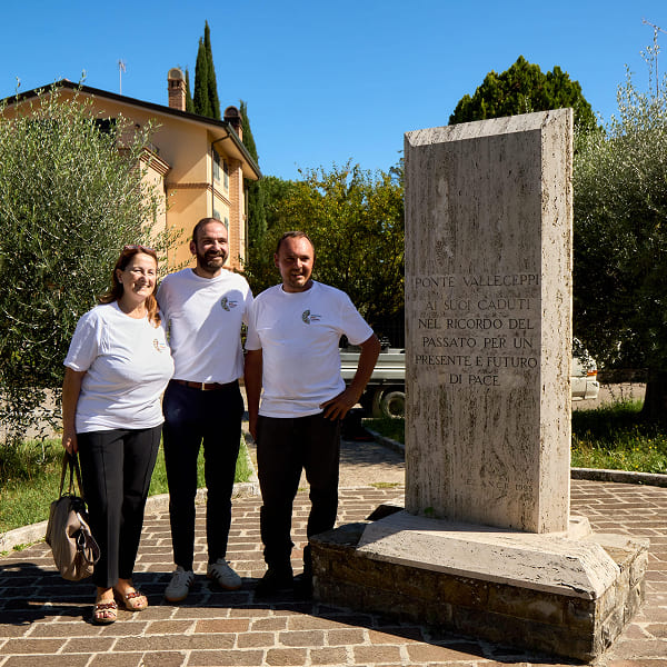 Three volunteers posing next to a stone monument