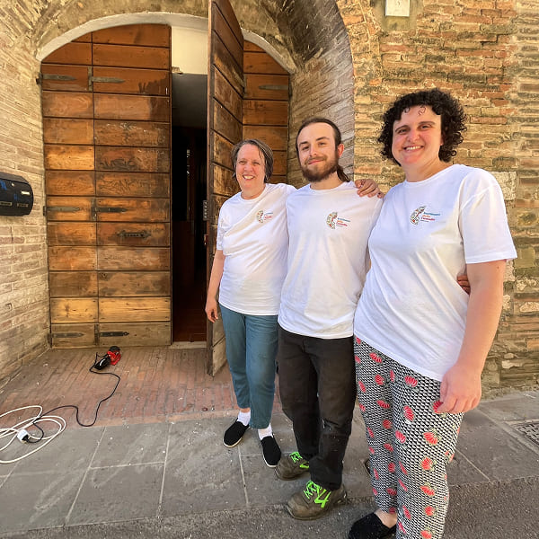 Three smiling volunteers in front of a historic wooden door