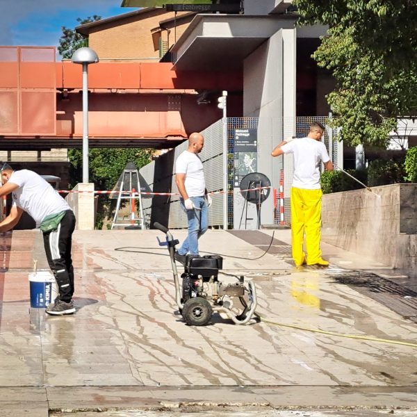 Three men cleaning a ramp with a pressure washer and sponges
