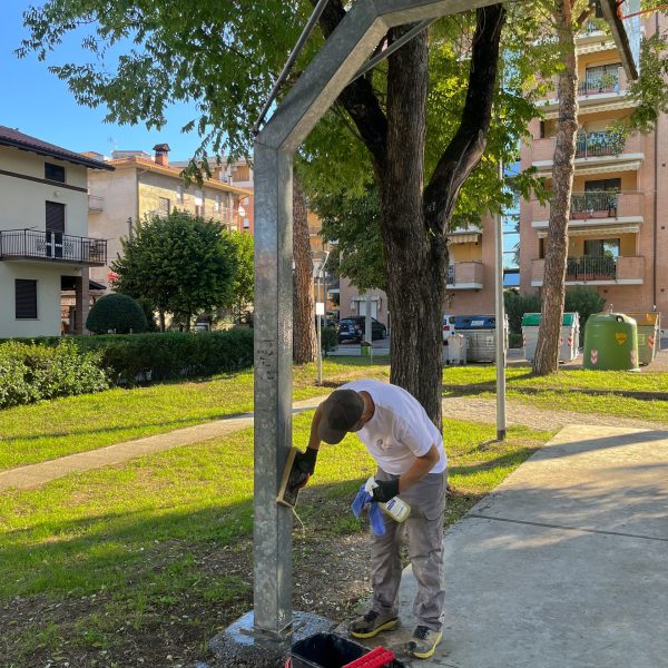 Man cleaning a basketball hoop in a residential green area