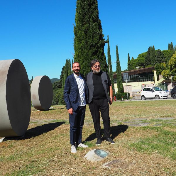 Two men standing next to circular sculptures